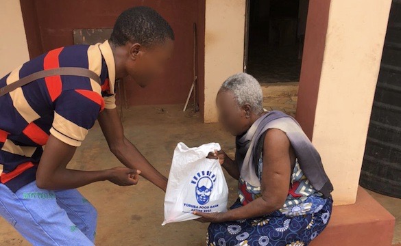 A volunteer hands a Yorùbá Food Bank parcel to an elderly woman