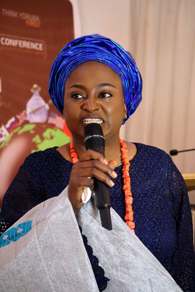 A speaker in a blue gèlè and coral beads at the 4th Annual Yorùbá Global Conference